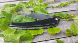 Couteau de collection à demi ouvert sur une belle lame en damas subtile qui constraste avec son manche en corne de buffle noir